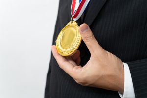 金メダルをぶらさげたスーツの男性
